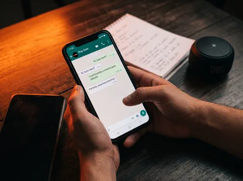 Mão segurando um celular com uma conversa de WhatsApp aberta
